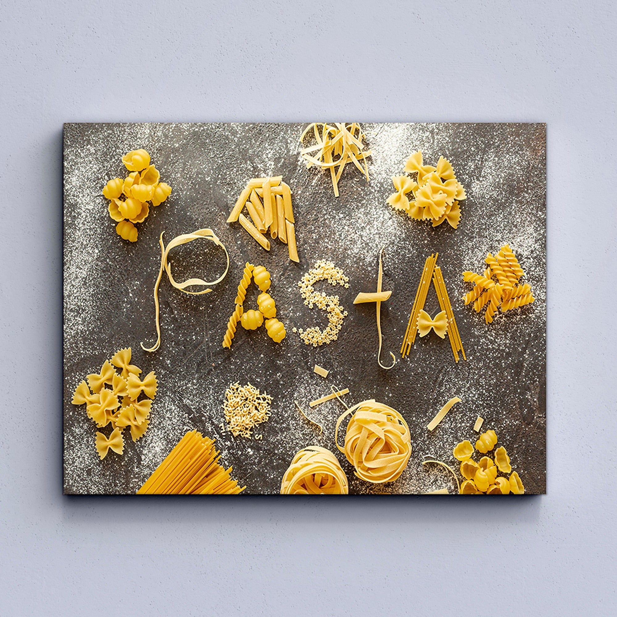 Various types of pasta arranged to spell out 'Pasta' on a textured surface.