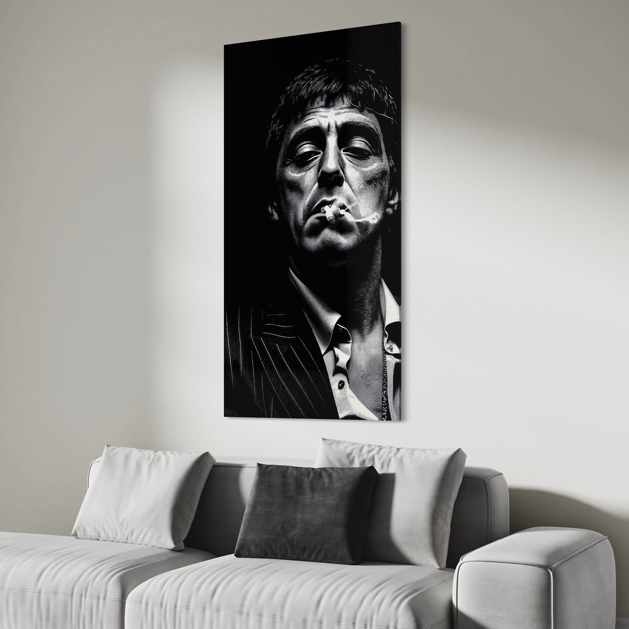 Black and white portrait of a man smoking above a gray sofa with cushions.
