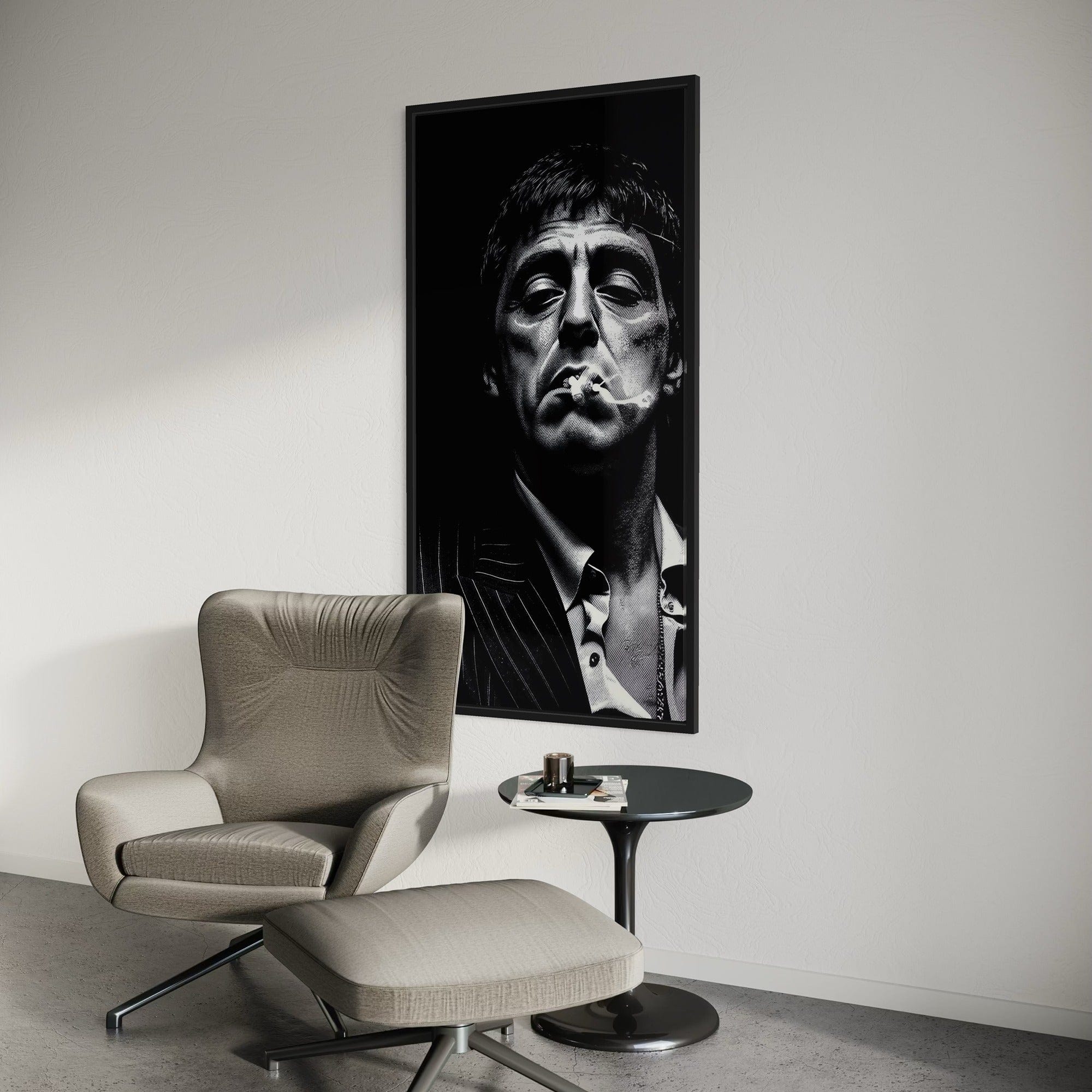 Modern interior with a gray armchair and ottoman, a small round table, and a framed black and white portrait on the wall.