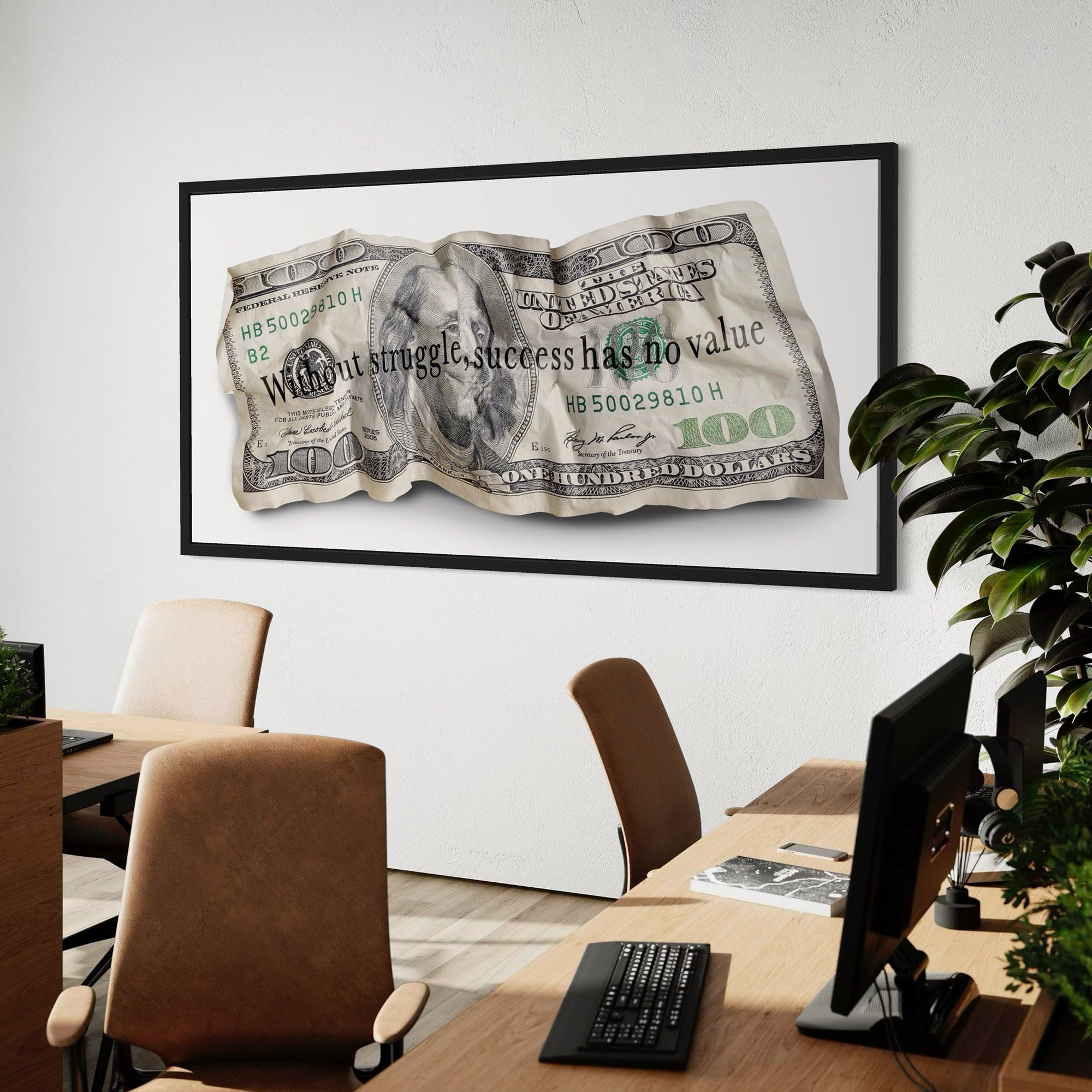 Framed dollar bill artwork above a desk in an office setting