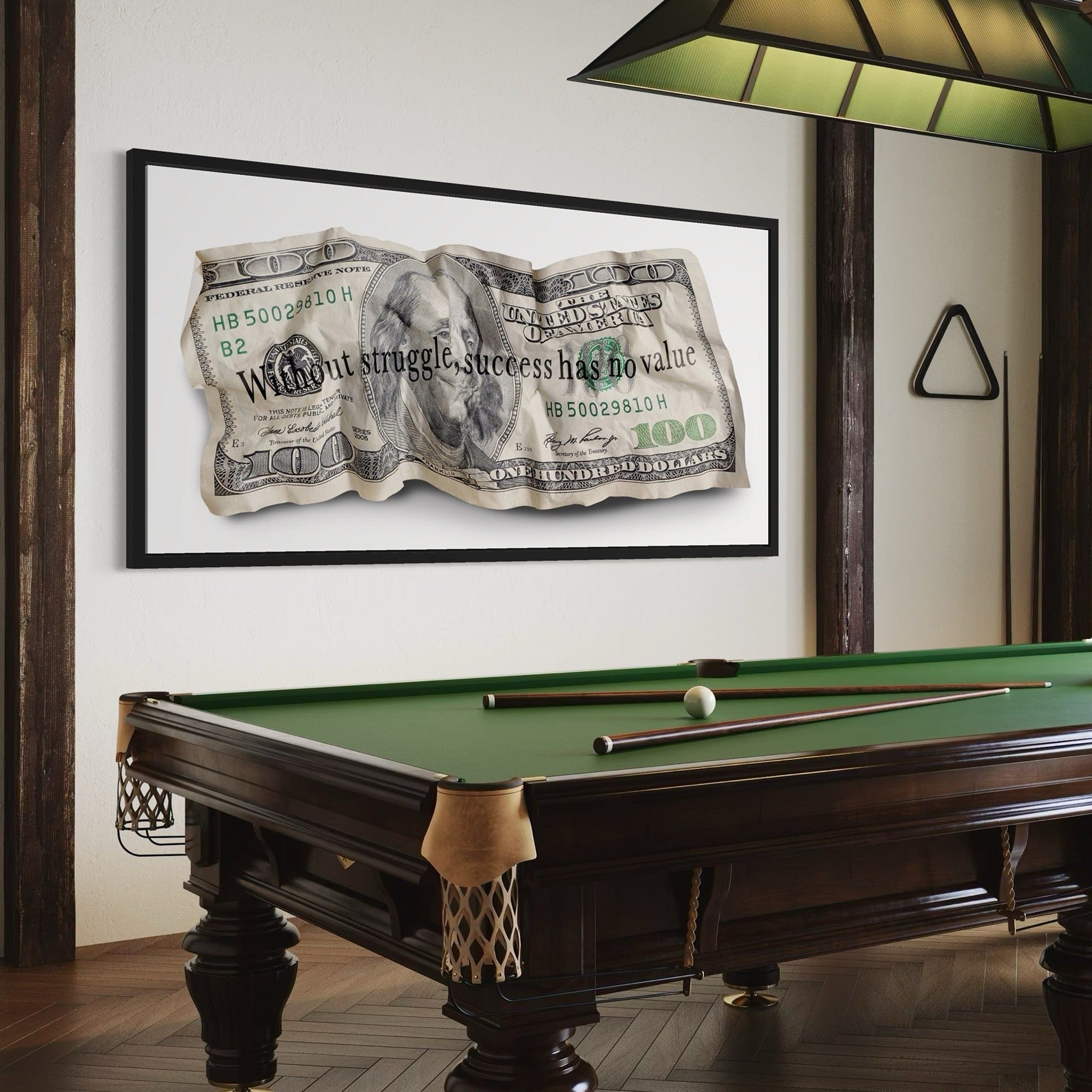 Framed dollar bill artwork above a pool table in a room.