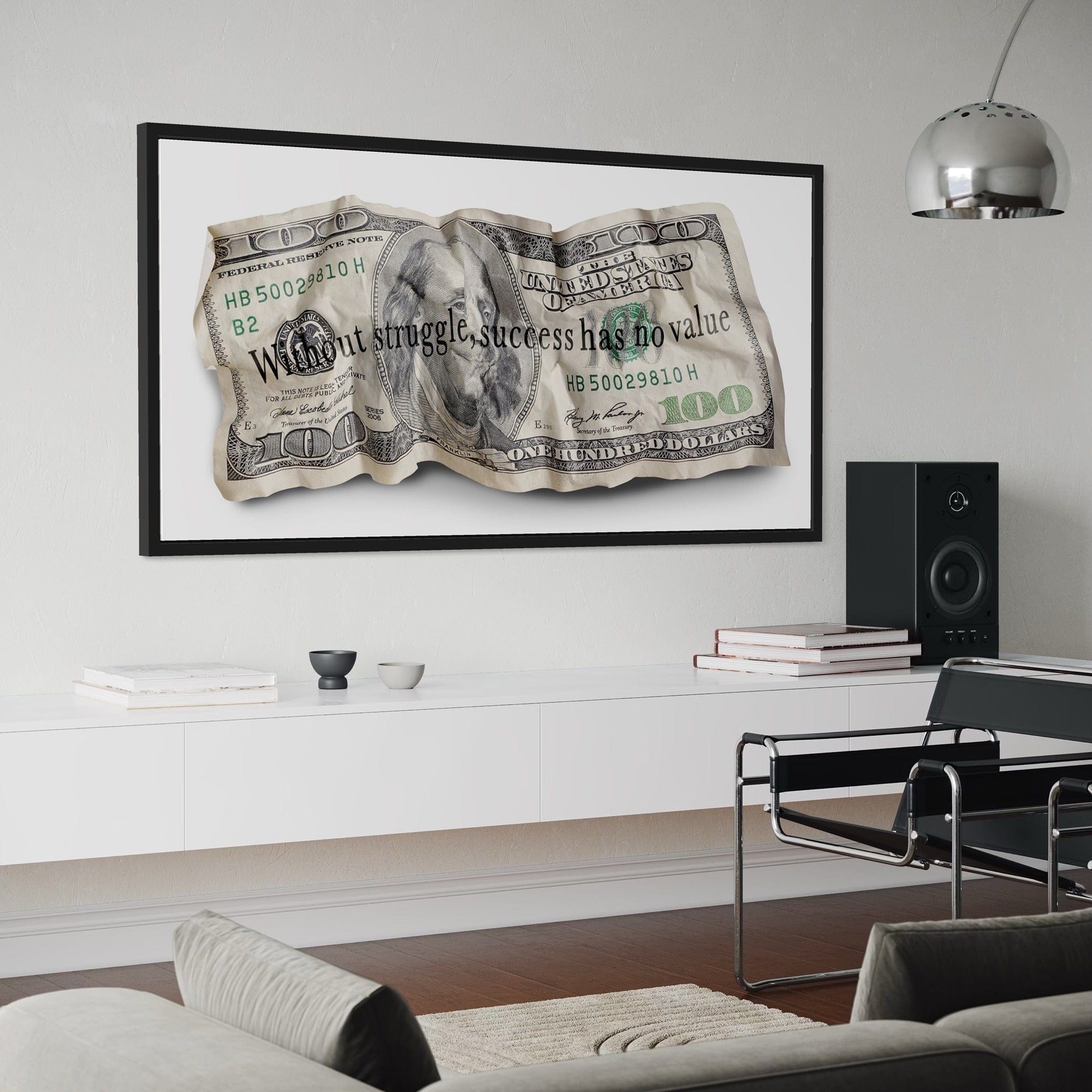 Framed artwork of a crumpled dollar bill with motivational quote in a modern living room.