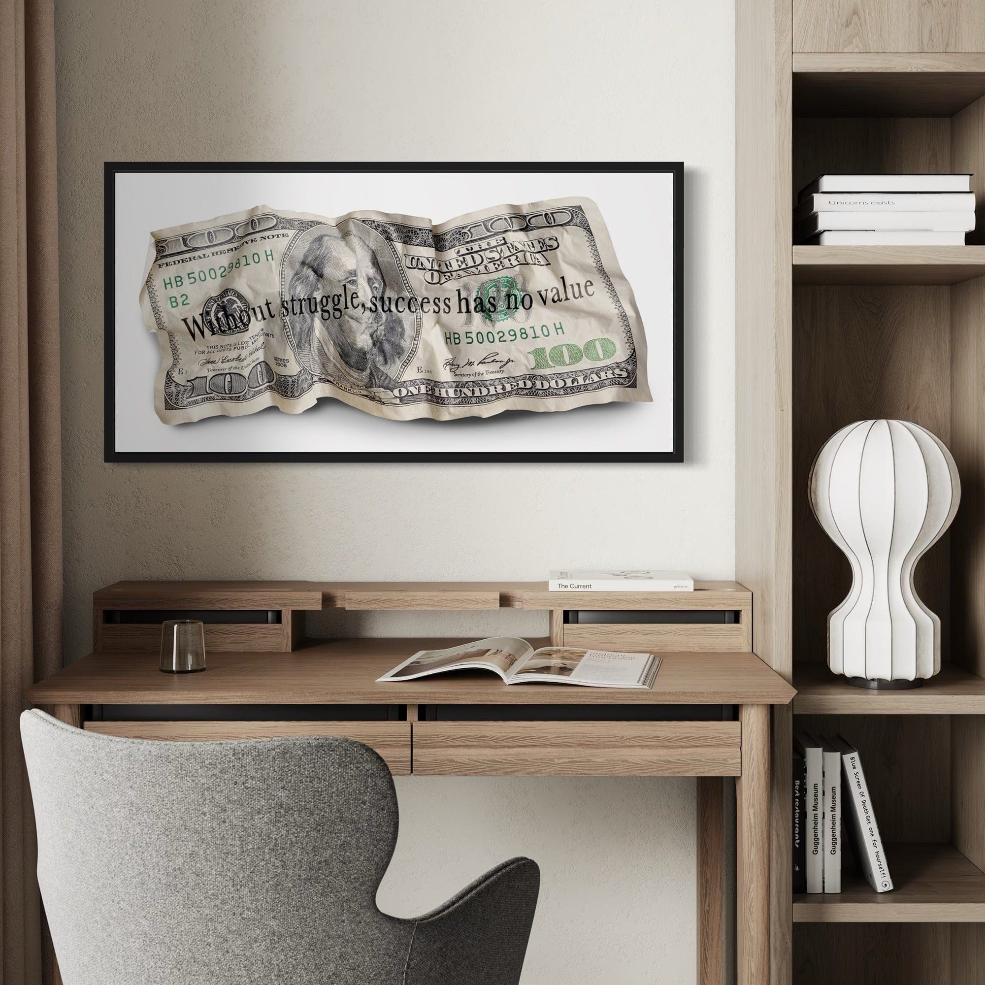 Framed dollar bill artwork above a desk in a home office setting.